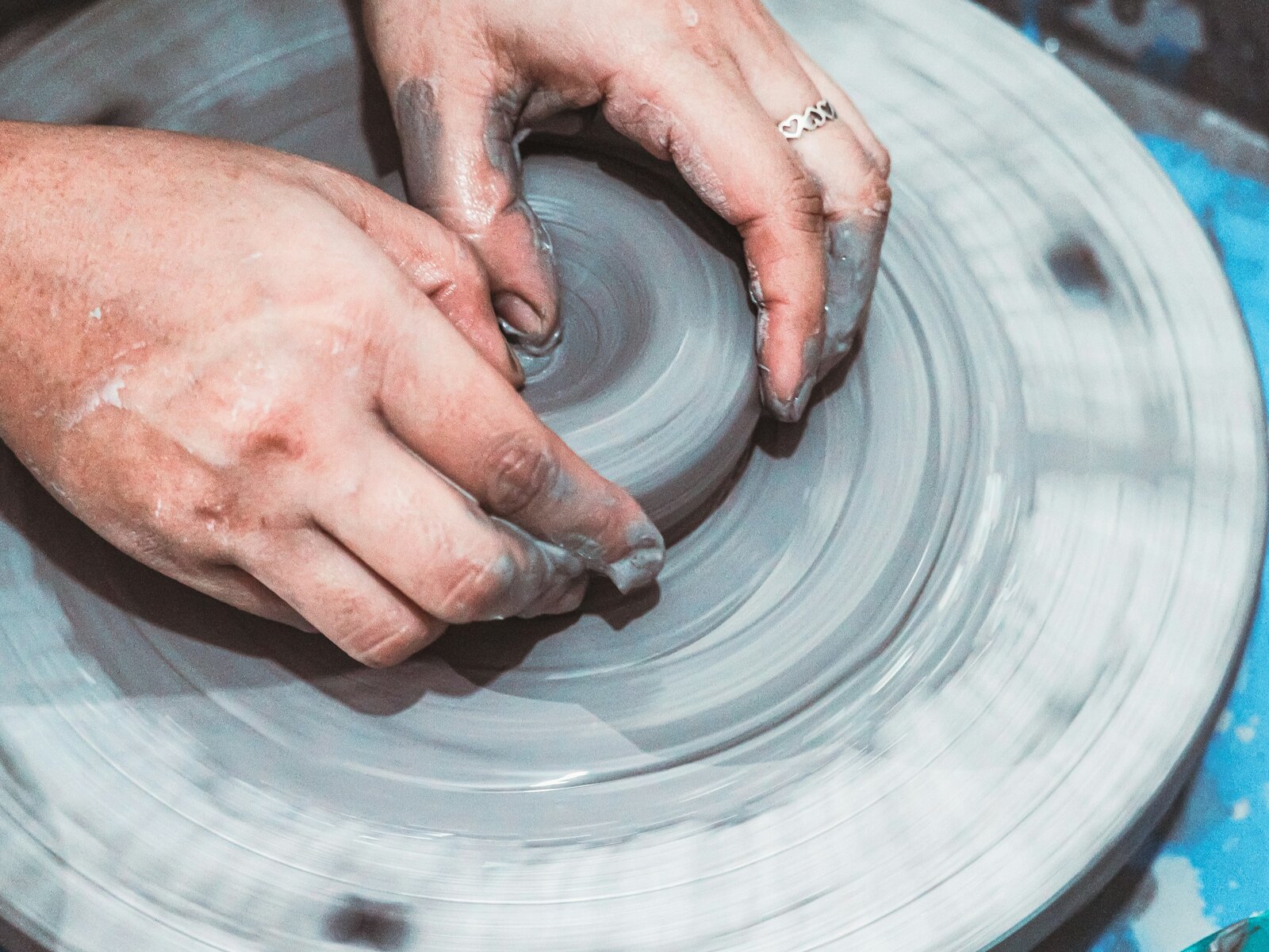 Hands shaping wet clay on a pottery wheel